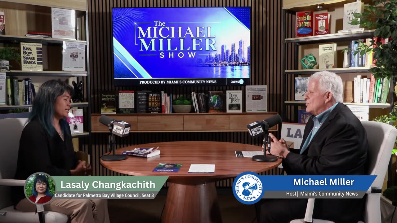 Lasaly Changkachith and host Michael Miller seated at a table in the Miami's Community News studio